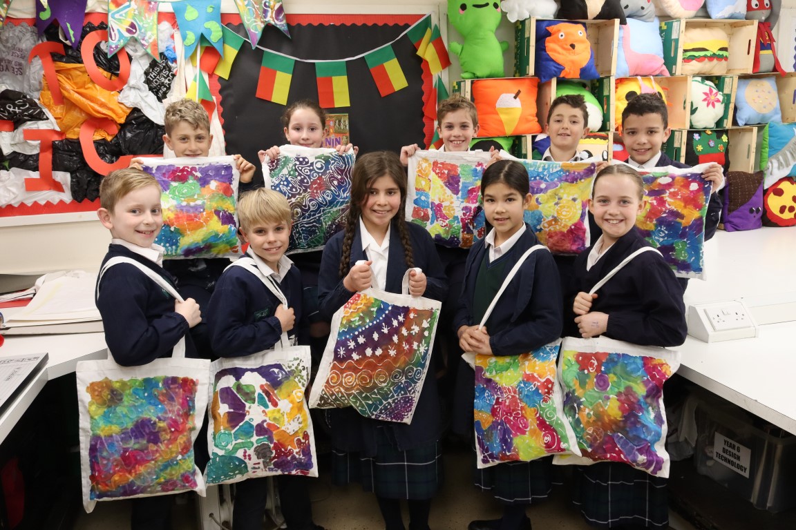 pupils pose with their colourful tote bags dyed with the flour resist method in textiles lessons