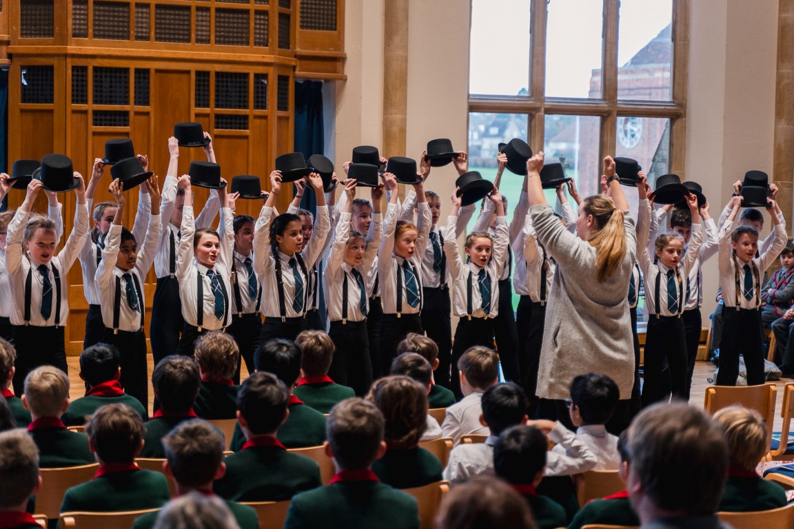 children hold their top hats above their heads while singing Puttin On The Ritz at Bedford School