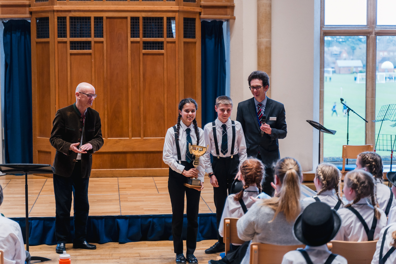 Girl and boy choir captains receive a trophy from Bob Chilcott at the Bedford Choral competition