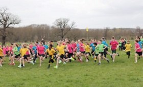 children in blue, yellow, green and pink t-shirts representing their Houses run across the Woodhall Estate for Heath Mount's annual cross country race