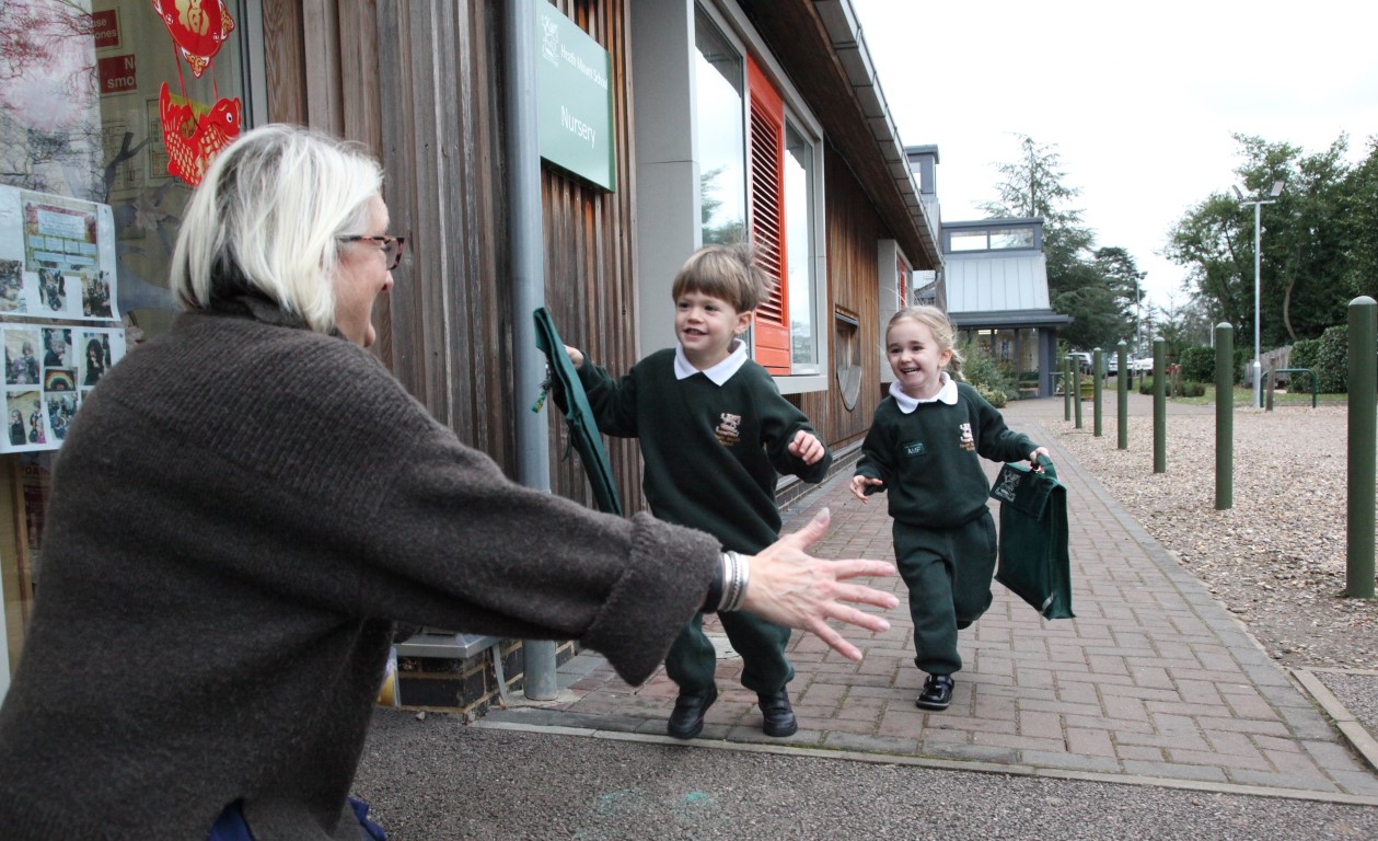 Nursery boy and girl pupils run happily into the arms of our Head of Nursery.  