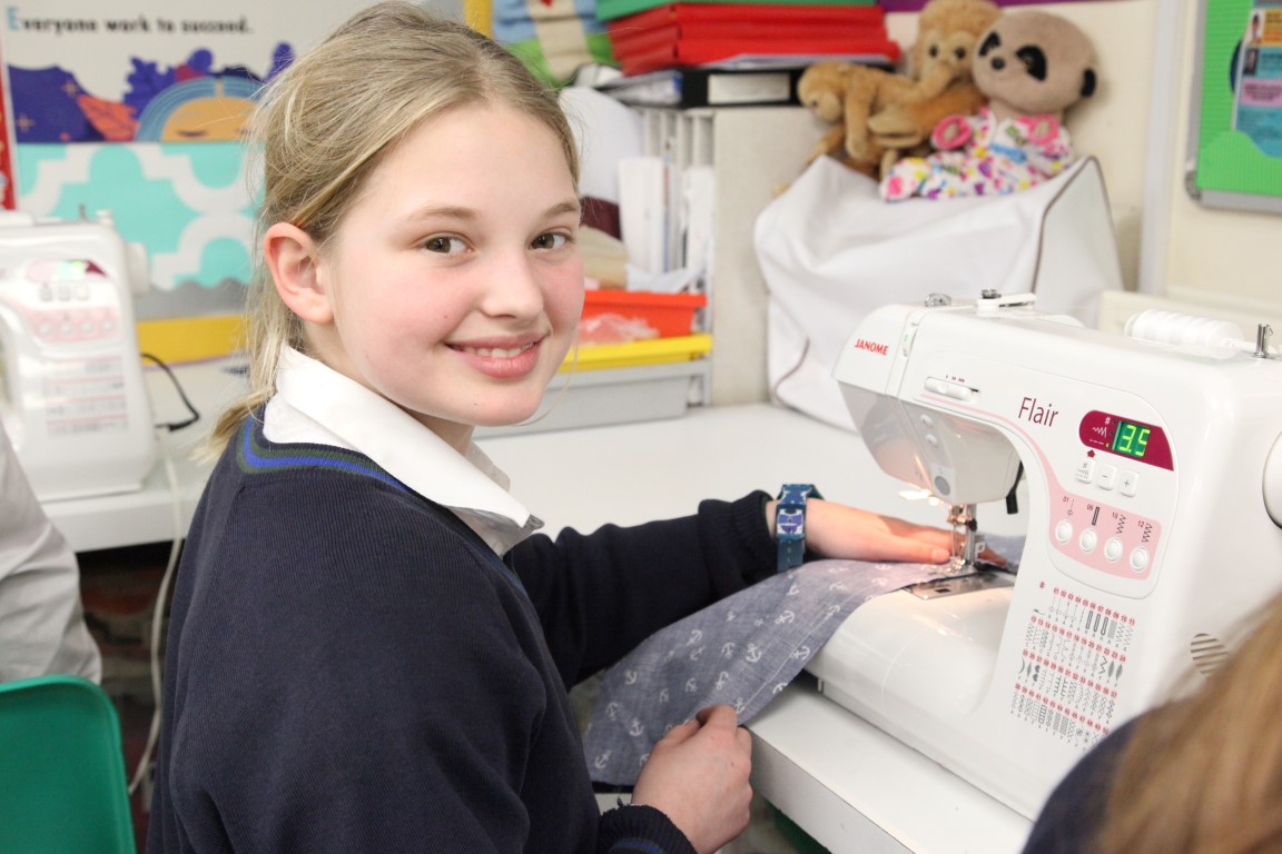 a senior girl works on some pyjama bottoms using the sewing machines in the textiles room