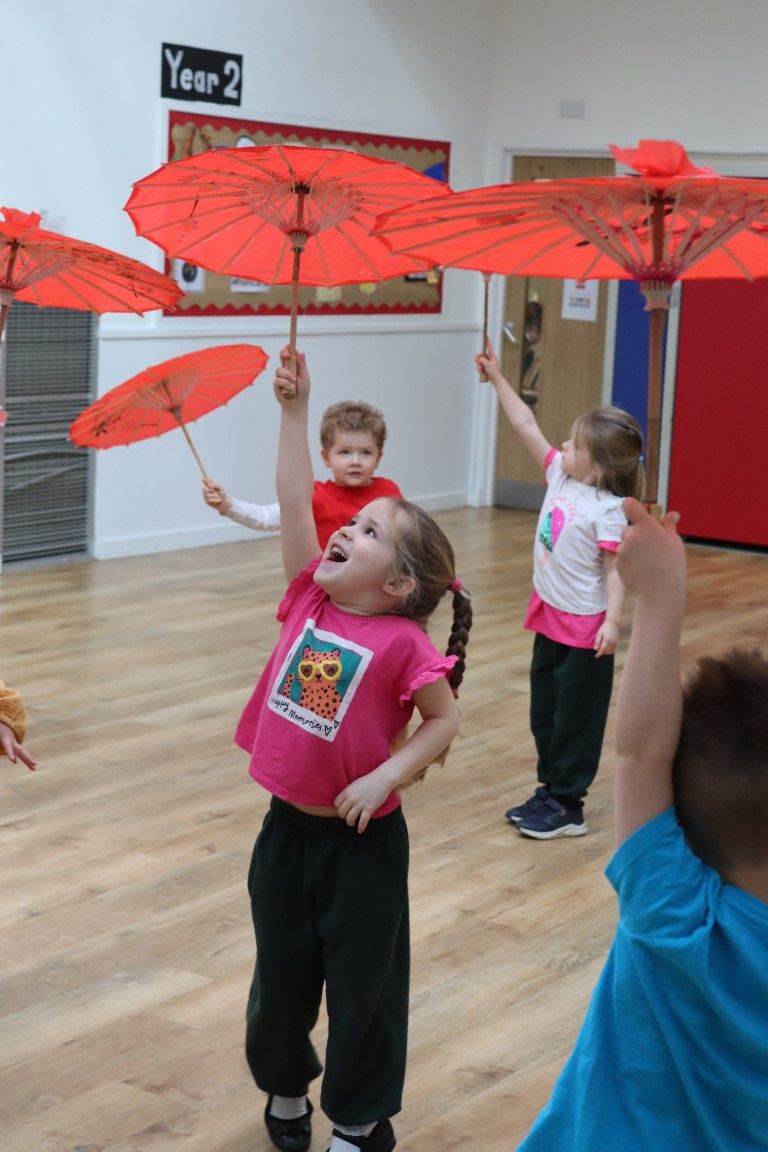 A Nursery girl holds up her Chinese parasol high in the air during a dance workshop