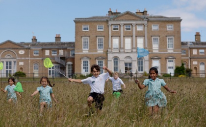 Young children run in the fields in front of Heath Mount School Grade I listed mansion house in the grounds of the Woodhall Park Estate