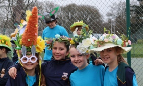 four girls pose in their easter bonnets including a giant carrot design and lots of spring flowers