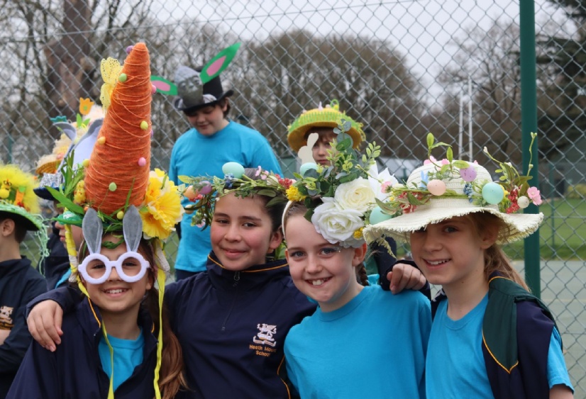 four girls pose in their easter bonnets including a giant carrot design and lots of spring flowers