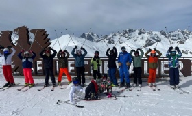 Pupils in skiwear pose in front of a snowy backdrop and a big sign saying Serre Chevalier