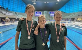 National Butterfly champion is pictured wearing his gold medal flanked by two fellow pupils who won silver at the London Aquatic Centre